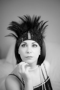 Beautiful woman wearing jewelry and headband looking away while sitting on bed against wall