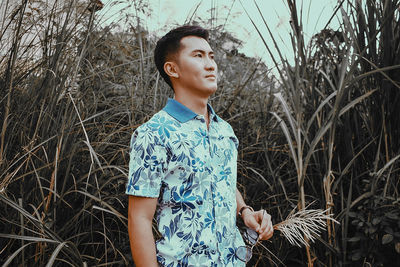 Happy boy standing against plants against sky