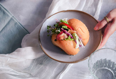 Cropped hand holding burger in plate