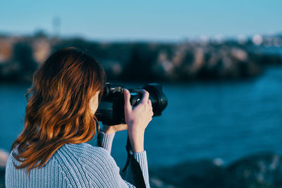 Rear view of woman photographing sea