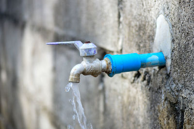 Close-up of water faucet against wall