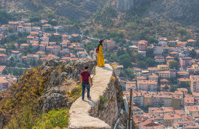 Rear view of men standing on mountain against buildings in city