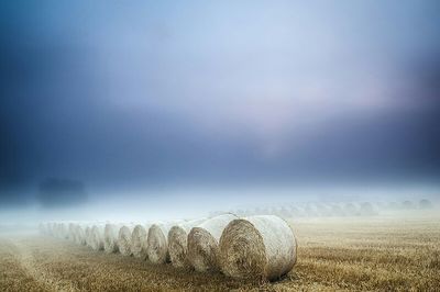 Hay bales on field against sky