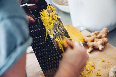 Cropped hands grating ginger