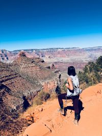 Rear view of woman sitting on chair against clear sky