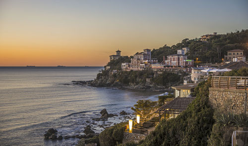 Scenic view of sea and buildings against sky during sunset