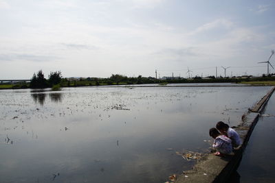People on shore against sky