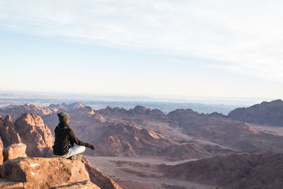 Rear view of man looking at mountains against sky