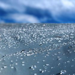 Close-up of wet glass against blue sky