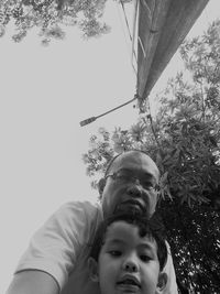 Low angle portrait of boy by plants against trees