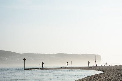 People on beach against clear sky