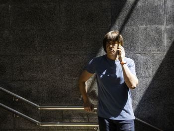 Serious man is listening to somebody by his smartphone in underground pedestrian crossing. 