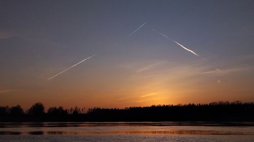 Scenic view of vapor trails in sky during sunset