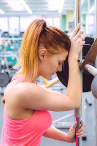 Woman standing by pole in gym