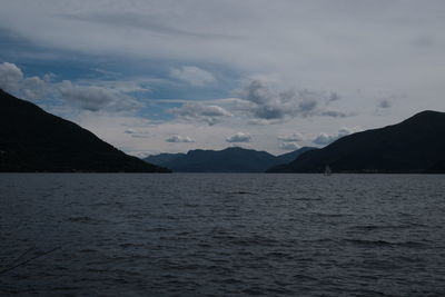 Scenic view of sea by mountains against sky