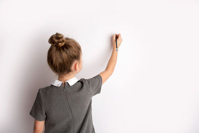 Rear view of girl standing against white background