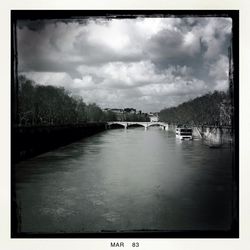 Bridge over river against cloudy sky