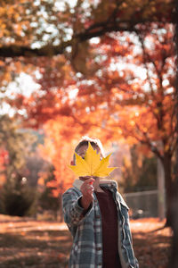 Person holding maple leaf during autumn