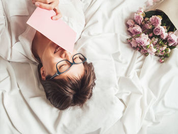 Smiling woman in bed with roses, letter in pink envelope. valentine day or happy birthday surprise.