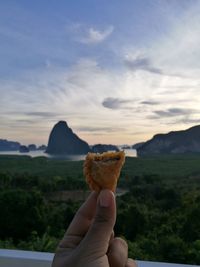 Close-up of hand holding snack against mountains