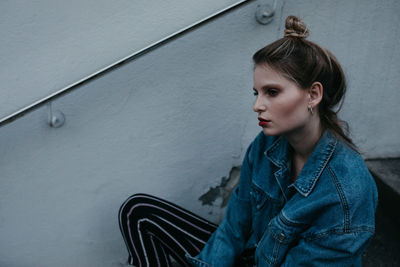 Thoughtful woman wearing denim jacket while sitting outdoors