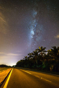 Road amidst trees against sky at night