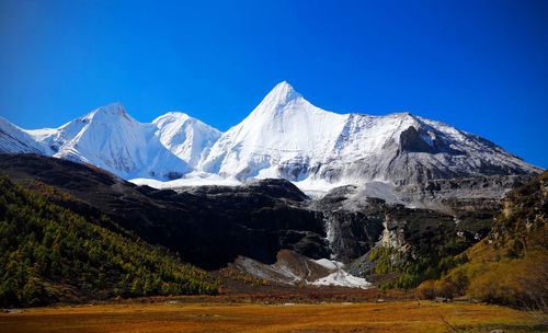 Scenic view of snowcapped mountains against clear blue sky