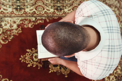 Directly above shot of man reading koran in mosque