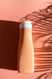 One bottle of liquid soap on a peach background.
