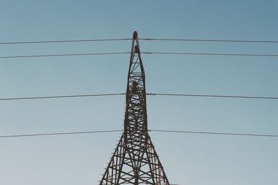 Low angle view of electricity pylon against clear blue sky