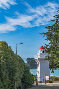 Lighthouse by sea against sky