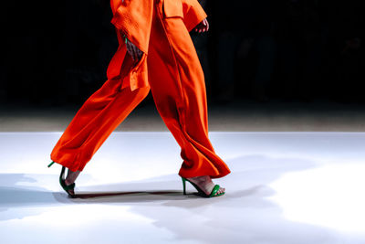 Stylish women's look orange pants, blouse and green high heels