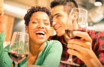 Smiling friends holding wineglasses while sitting in restaurant