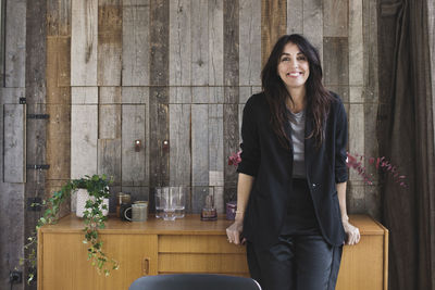 Portrait of happy businesswoman leaning on sideboard against wood paneling in portable office truck