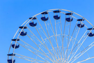 Low angle view of ferris wheel against clear blue sky