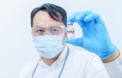 Young doctor or scientist in gown shirt holding covid-19 vaccines.