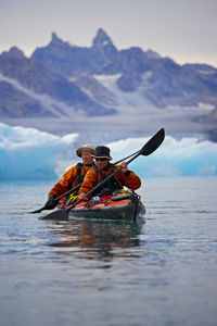 2 men traveling on a sea-kayak though the fjords of eastern greenland