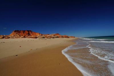 Scenic view of beach against clear blue sky