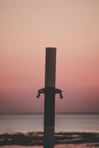 Close-up of silhouette metal on beach against sky during sunset