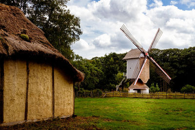 Traditional windmill on landscape against sky