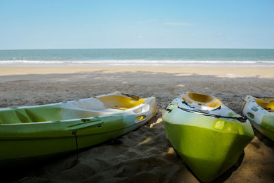 A green kayak parked in the sand by the tropical sea 