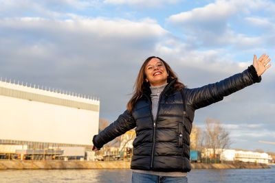 Middle aged woman wearing winter clothes taking fun by a river - people in recreation concept