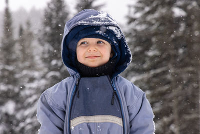 Portrait of smiling young woman standing against trees during winter