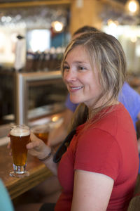 A young woman enjoys a beer with her friends at a bar in oregon.