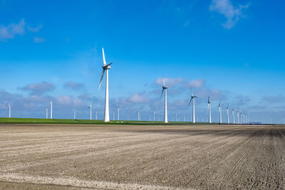 Wind turbines on field against blue sky