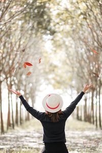 Woman with arms outstretched standing against plants