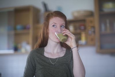 Young woman making smoothie and drinking