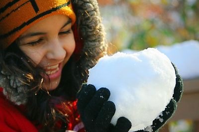 Close-up of cheerful girl holding snow ball