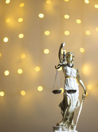 Close-up of lady justice statue against illuminated lights