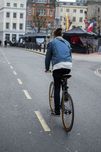 Rear view of woman riding bicycle on road